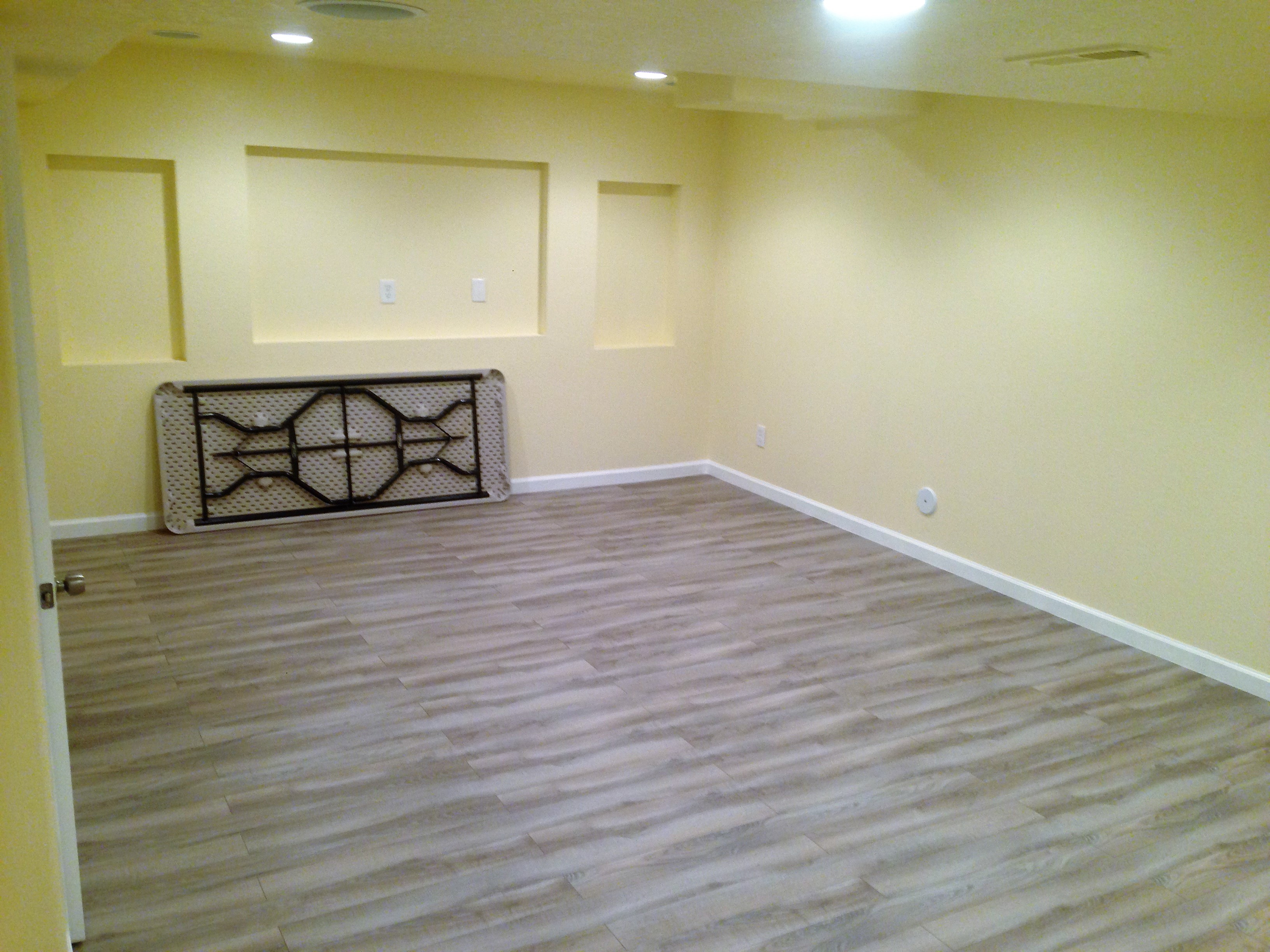 Walls, floors, and baseboards are installed in the basement