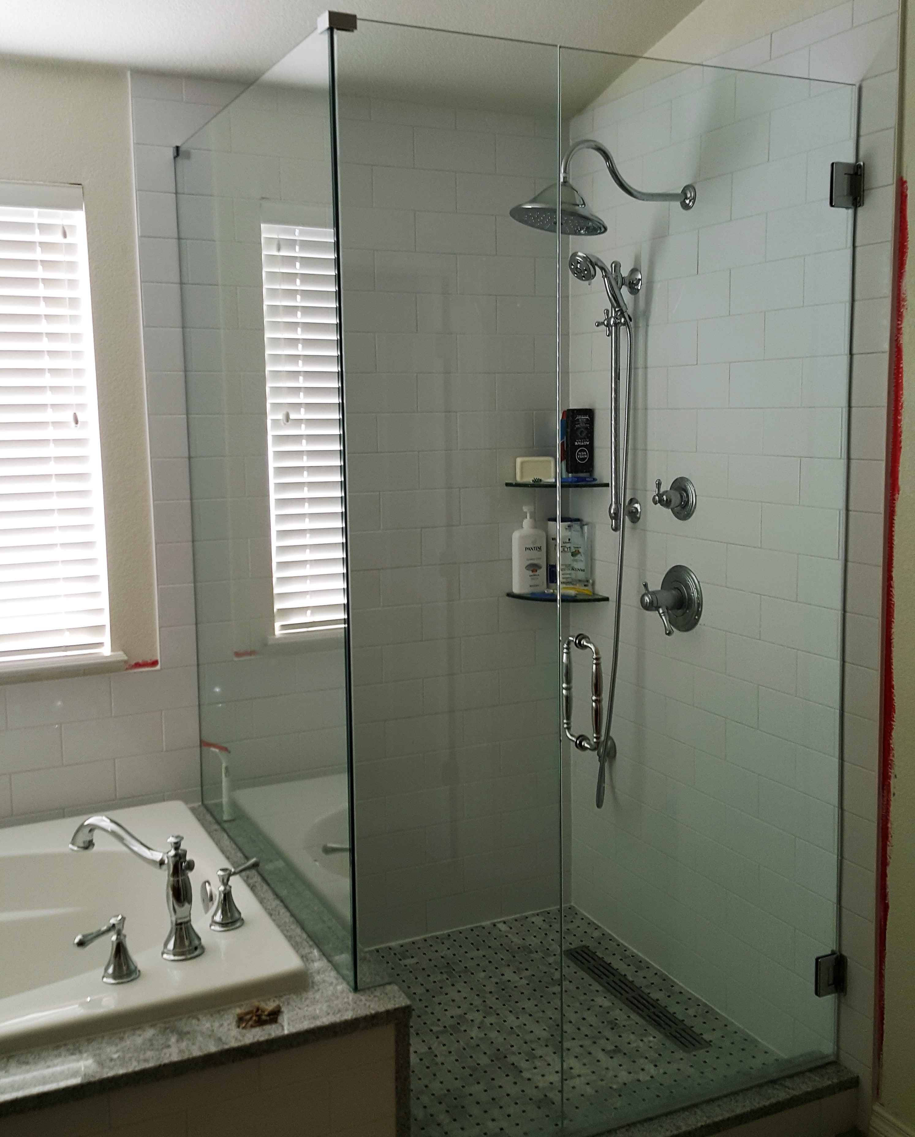 corner glassed shower with chrome fixtures and bathtub to the left