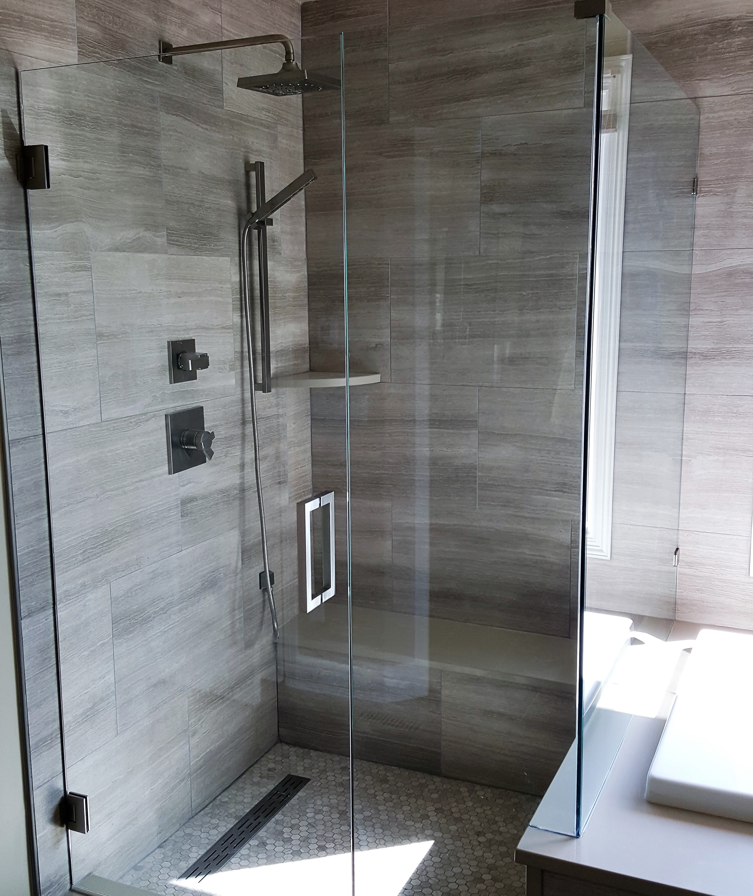 corner glassed shower with a bench and chrome fixtures