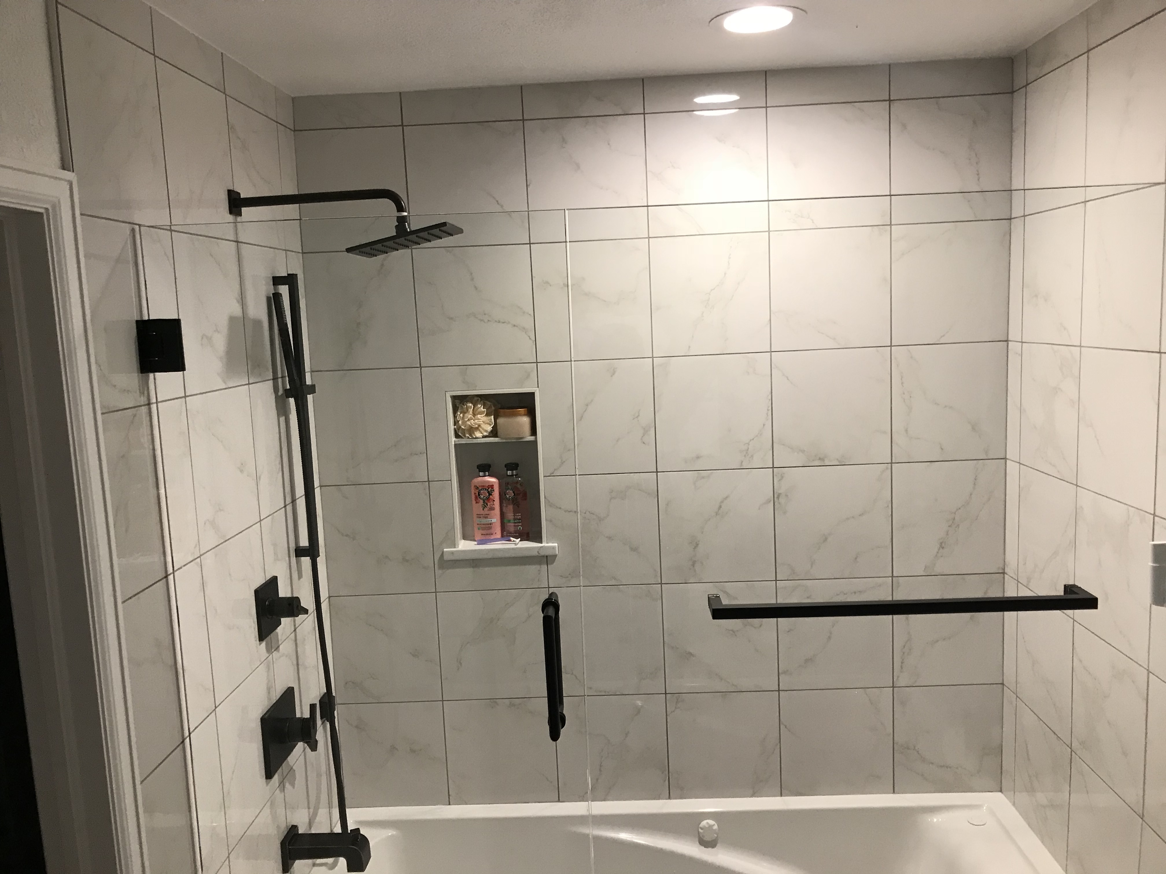 bathtub and a shower with white tiles and black shower fixtures